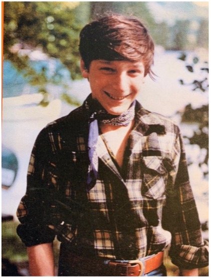 a young teen wearing a plaid shirt and a neckerchief